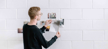 jongeman hangt foto's op aan muur in studio