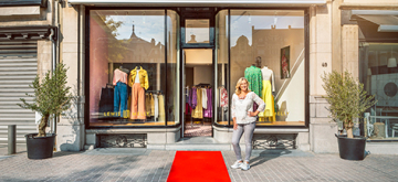 vrouw voor etalage van haar kledingwinkel