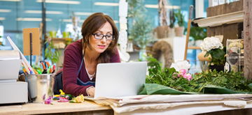 vrouw in bloemenzaak werkt op laptop