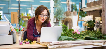 Florist in winkel met laptop