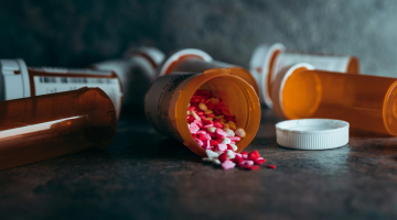 Open potje medicijnen verspreid over tafel