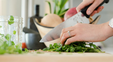 vrouw snijdt kruiden in de keuken