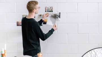 jongeman hangt foto's op aan muur in studio