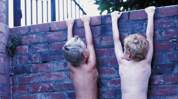 twee jongetjes kijken over een muur
