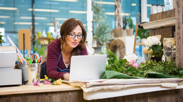 vrouw in bloemenzaak werkt op laptop