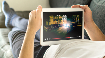 Man ligt naar video te kijken op tablet